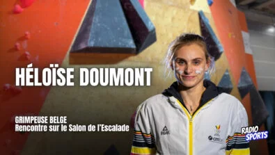 Héloïse Doumont, grimpeuse belge, photographiée au Salon de l’Escalade 2026 à Paris devant un mur de bloc.