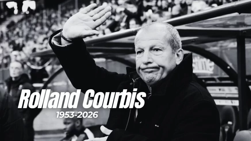 Portrait en noir et blanc de Rolland Courbis saluant le public, avec dates 1953-2026.